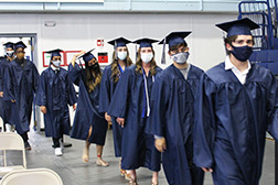 Otero graduates walking to their seats in the gym wearing face coverings