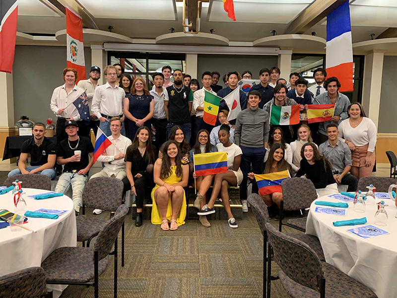International students in banquet hall holding different country flags.