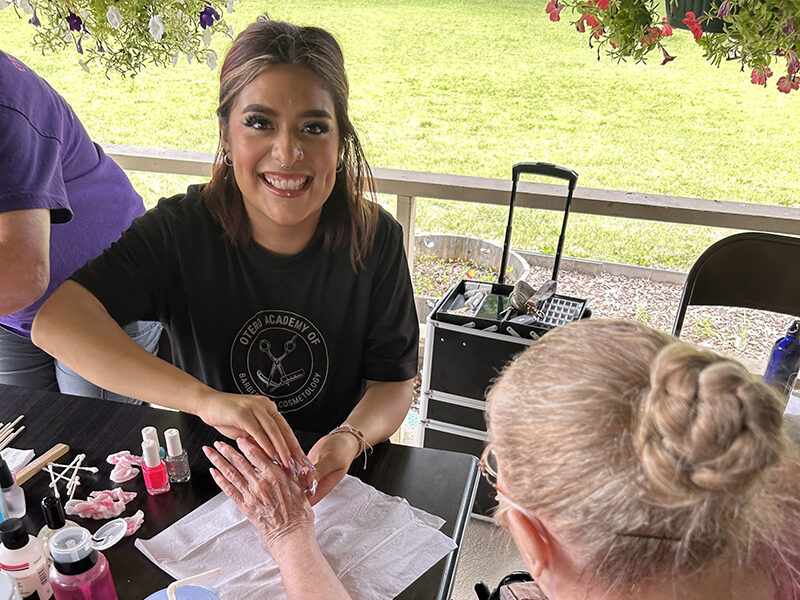 Cosmetology student gives a resident of Pioneer Health Care Center a manicure.