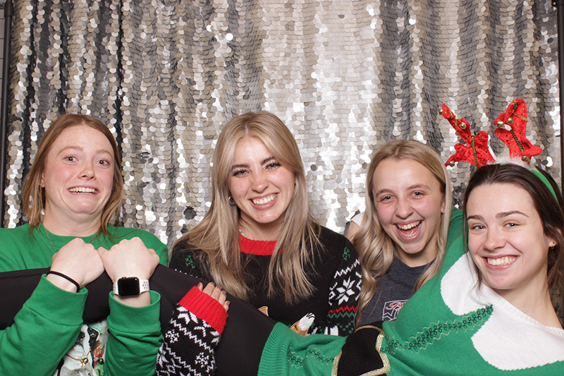 Four students are pictured dressed as elves in green outfits.
