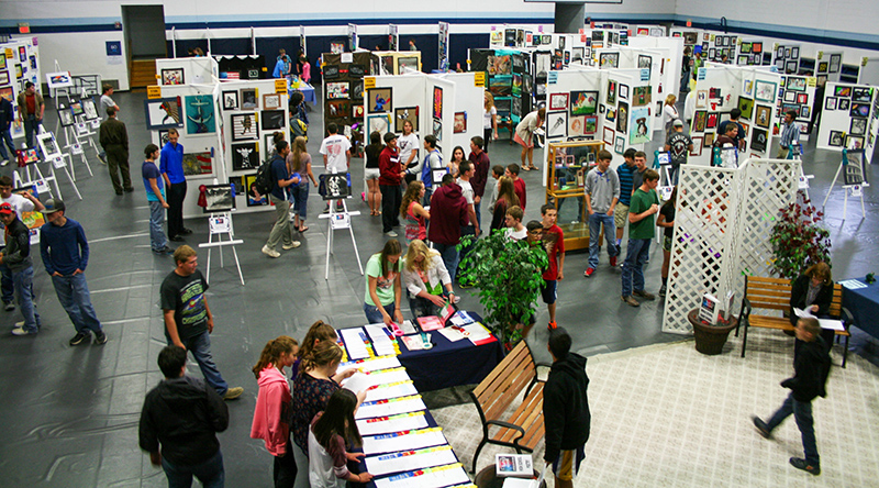 A photo of the students observing artwork set up inside a gym.