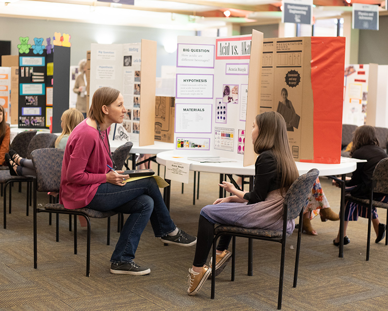 A mentor and a student look over a science fair project.