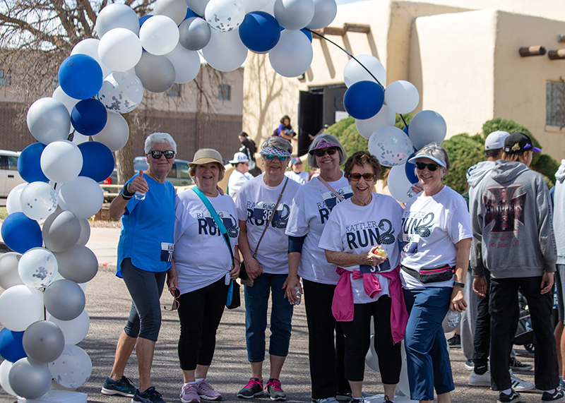 A group of women standing under a balloon arch after completing a 5K.